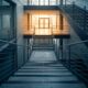 Aufsteigende Treppe in moderner Architektur Richtung Lichtausgang — visualisiert den Private-Debt-Mandatsprozess vom Term Sheet zum Closing.