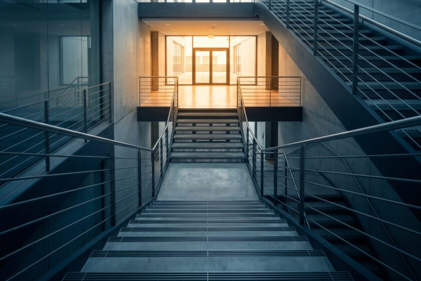 Aufsteigende Treppe in moderner Architektur Richtung Lichtausgang — visualisiert den Private-Debt-Mandatsprozess vom Term Sheet zum Closing.